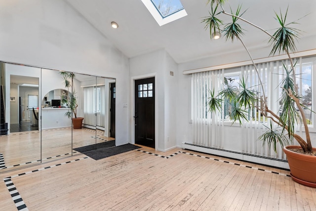 entryway with high vaulted ceiling, a skylight, wood-type flooring, and a baseboard radiator