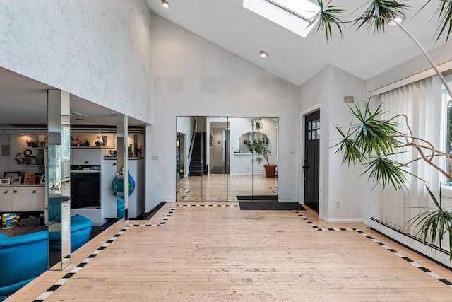 entrance foyer featuring baseboards, stairway, baseboard heating, a skylight, and hardwood / wood-style flooring