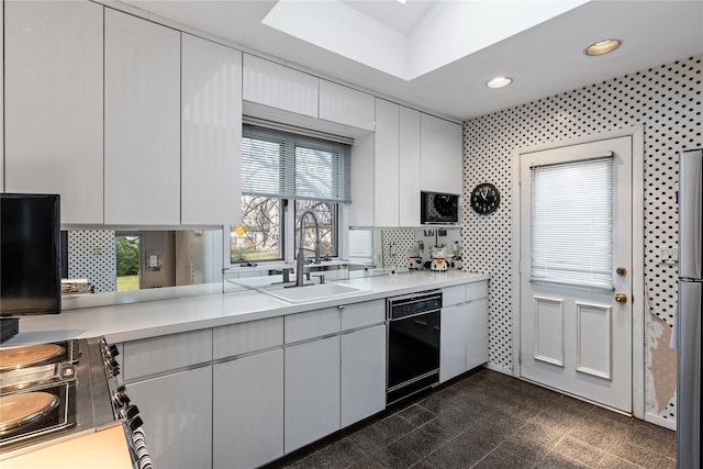 kitchen with electric range, a sink, granite finish floor, light countertops, and dishwasher