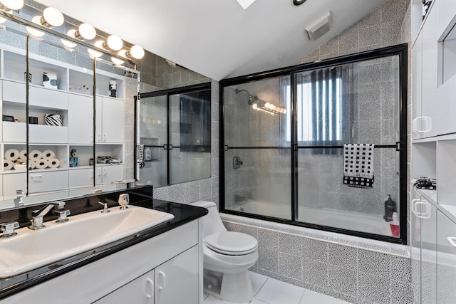 full bath with vanity, tile patterned flooring, vaulted ceiling, tiled shower / bath combo, and toilet