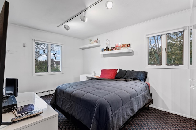 carpeted bedroom featuring baseboard heating, multiple windows, and baseboards