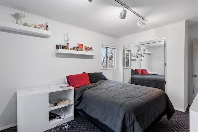 bedroom with ornamental molding, a closet, carpet, rail lighting, and baseboards