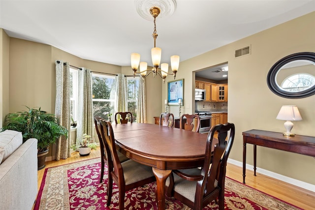 dining room featuring visible vents, an inviting chandelier, baseboards, and light wood-style floors