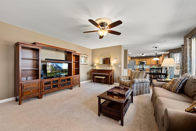 living room with a ceiling fan, baseboards, and light carpet