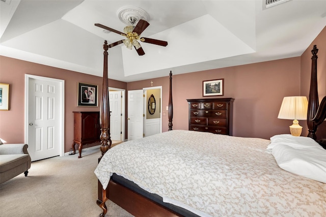 bedroom with a ceiling fan, a raised ceiling, light colored carpet, and visible vents