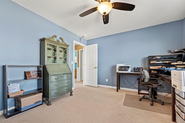 carpeted office space with a ceiling fan and baseboards