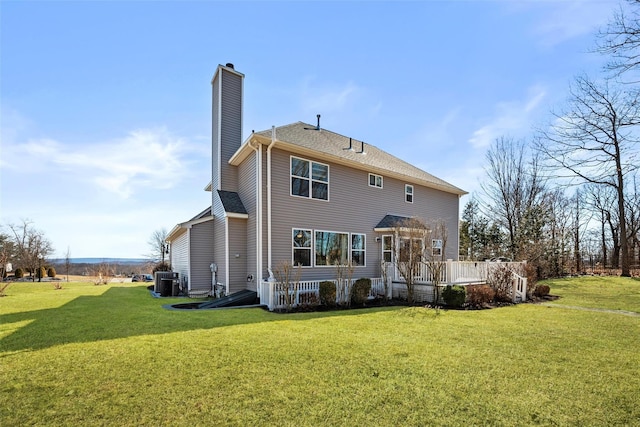 rear view of property with roof with shingles, central AC unit, a chimney, a deck, and a yard