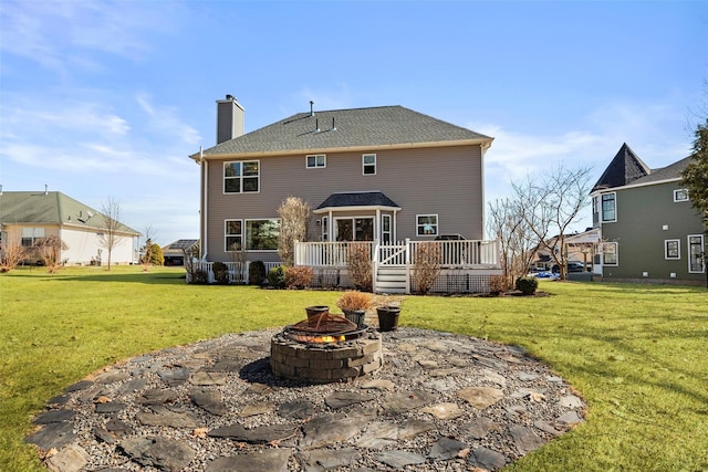 back of property with an outdoor fire pit, a chimney, a deck, a yard, and a patio area