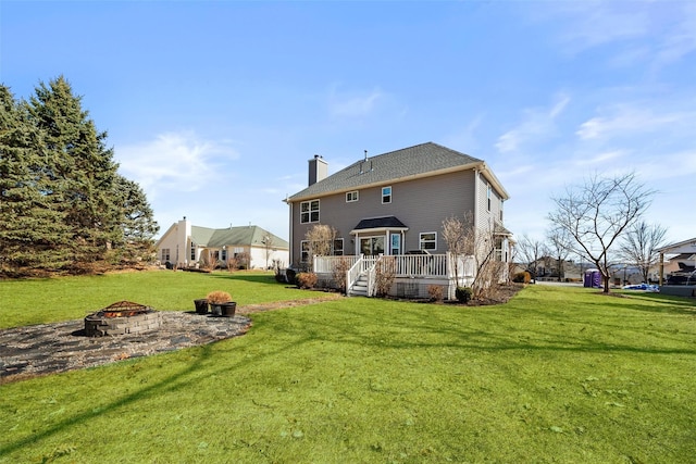 back of property with a chimney, a yard, an outdoor fire pit, and a deck