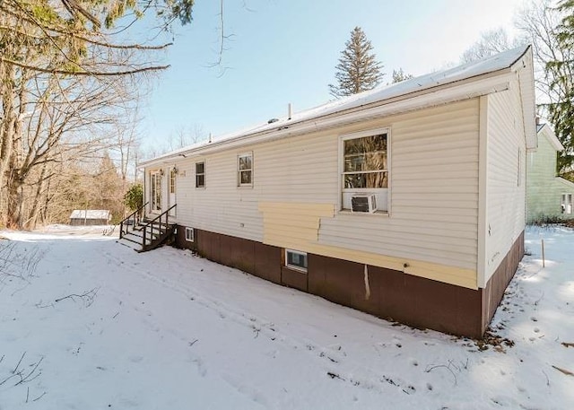 snow covered back of property featuring entry steps