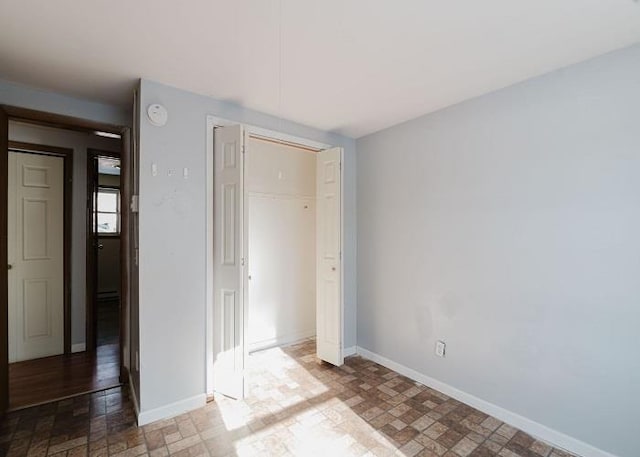 unfurnished bedroom featuring a closet, stone finish flooring, and baseboards