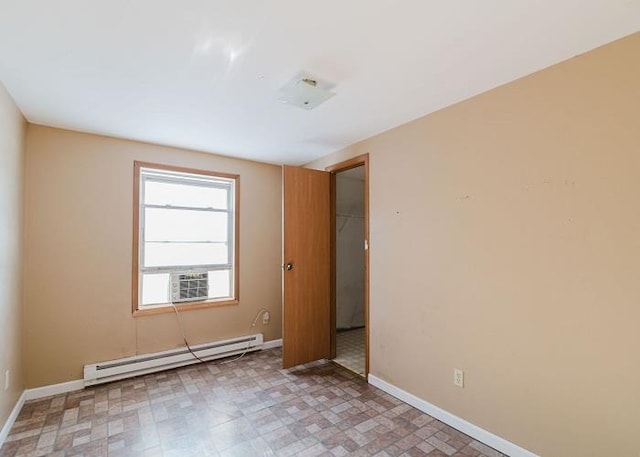 spare room featuring light floors, a baseboard heating unit, and baseboards