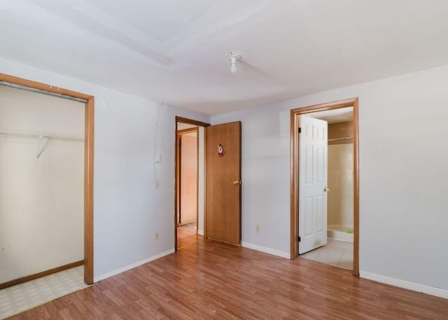 unfurnished bedroom featuring a closet, baseboards, and light wood-style flooring