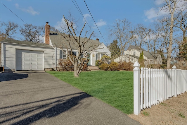 view of front of home with fence, an attached garage, a chimney, a front lawn, and aphalt driveway