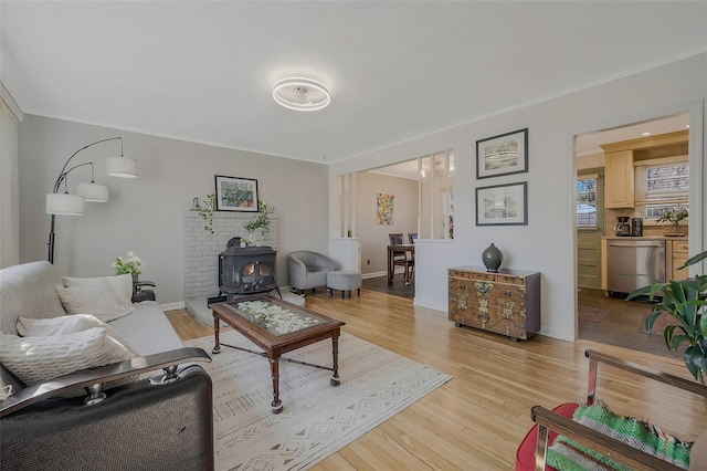 living area featuring light wood-type flooring, a wood stove, and ornamental molding