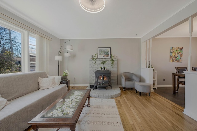 living area featuring a wood stove, light wood-style flooring, and baseboards