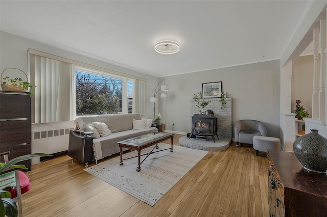 living room with baseboards, radiator heating unit, a wood stove, and wood finished floors