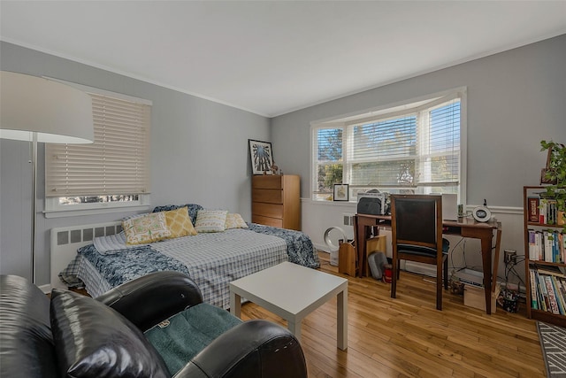 bedroom featuring ornamental molding, radiator, and hardwood / wood-style flooring