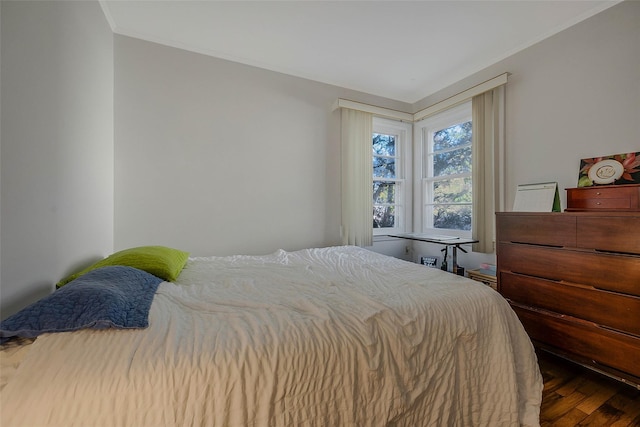 bedroom with wood finished floors and ornamental molding