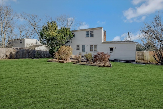 rear view of house featuring a lawn, fence, and a chimney