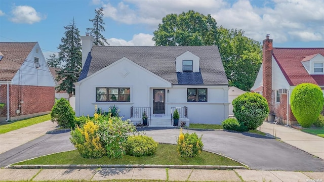 view of front facade featuring a shingled roof, aphalt driveway, and stucco siding