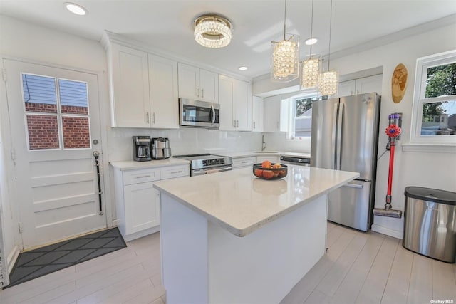 kitchen with a kitchen island, decorative backsplash, appliances with stainless steel finishes, and white cabinetry