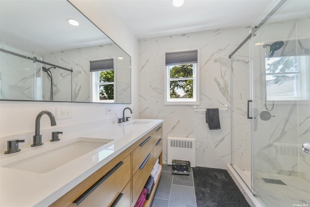 bathroom with a sink, a marble finish shower, a wealth of natural light, and radiator heating unit