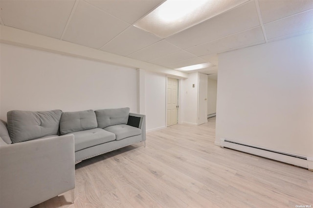 living room with a baseboard heating unit, a paneled ceiling, light wood-style floors, and baseboards