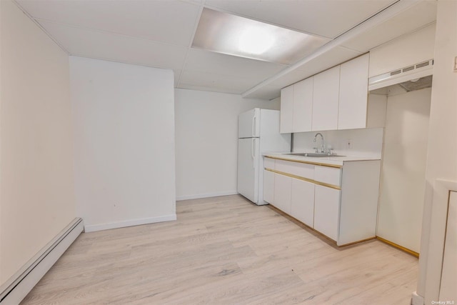 kitchen featuring a baseboard radiator, light wood-style flooring, freestanding refrigerator, a sink, and under cabinet range hood