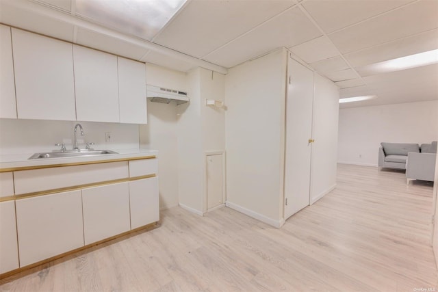 bathroom featuring wood finished floors, a paneled ceiling, baseboards, and a sink