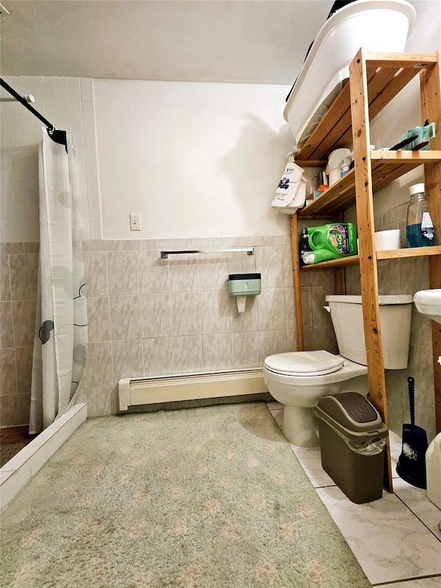 bathroom featuring a tile shower, baseboard heating, toilet, and tile walls