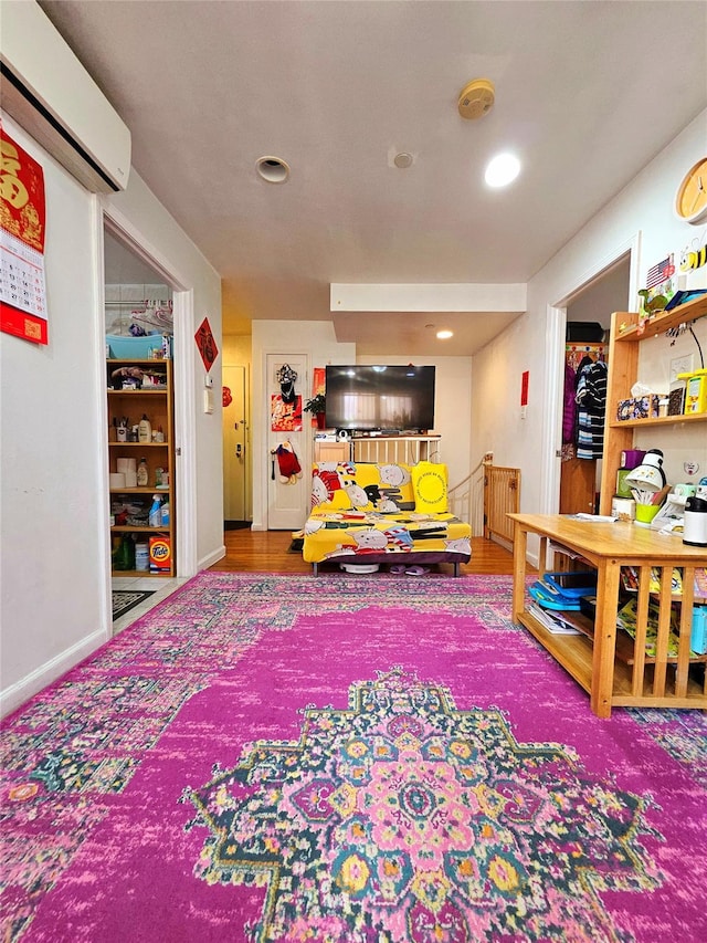 rec room with recessed lighting, wood finished floors, baseboards, and a wall mounted air conditioner