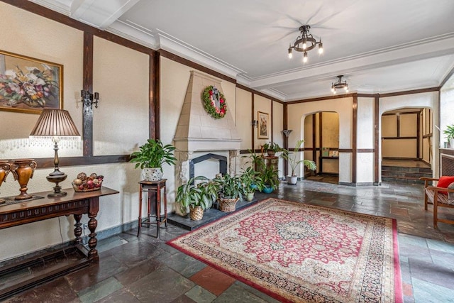 interior space with arched walkways, a fireplace with raised hearth, stone tile flooring, and ornamental molding