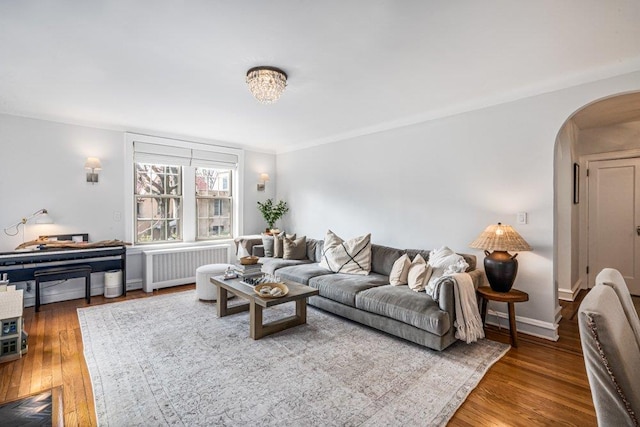 living area with hardwood / wood-style floors, radiator, baseboards, and arched walkways