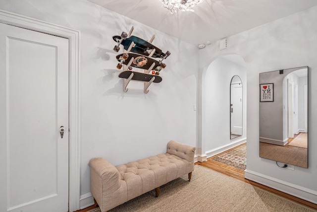 living area featuring wood finished floors, arched walkways, and baseboards