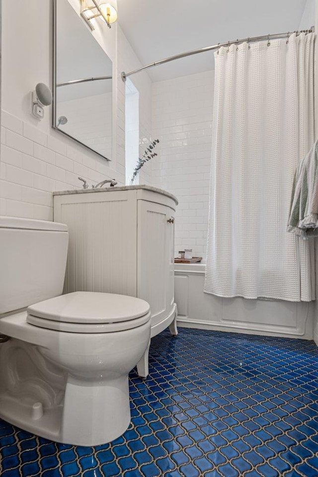 bathroom with tile patterned floors, toilet, shower / bath combo with shower curtain, and tile walls