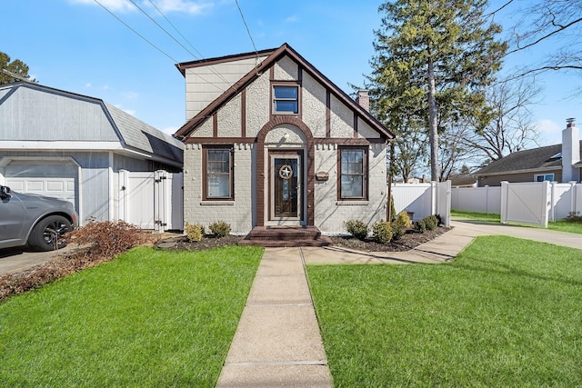 tudor-style house featuring fence, brick siding, a front lawn, and a gate