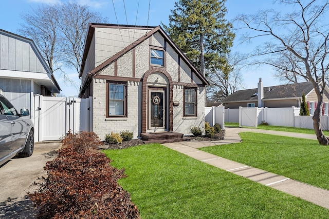 view of front facade with fence, brick siding, a front lawn, and a gate