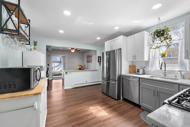 kitchen with a baseboard heating unit, recessed lighting, appliances with stainless steel finishes, dark wood-style floors, and a sink