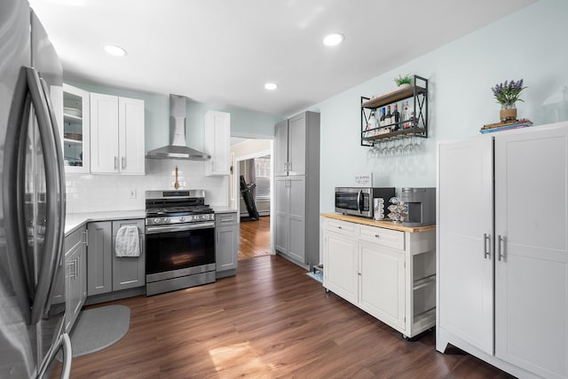 kitchen featuring light countertops, gray cabinets, stainless steel appliances, wall chimney exhaust hood, and dark wood-style flooring