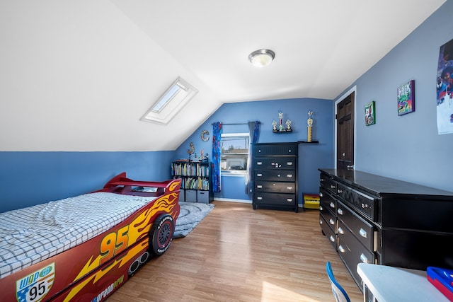 bedroom featuring lofted ceiling with skylight and wood finished floors