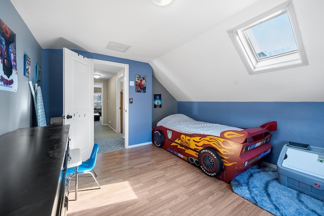 bedroom with light wood finished floors, multiple windows, lofted ceiling with skylight, and baseboards