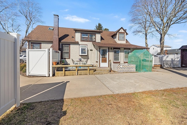 view of front of property featuring a patio, fence, an outdoor structure, and a gate