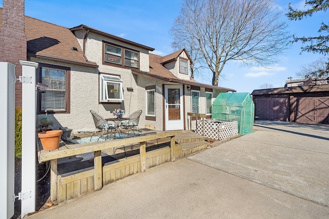 view of front of property with stucco siding, an outbuilding, and a patio area