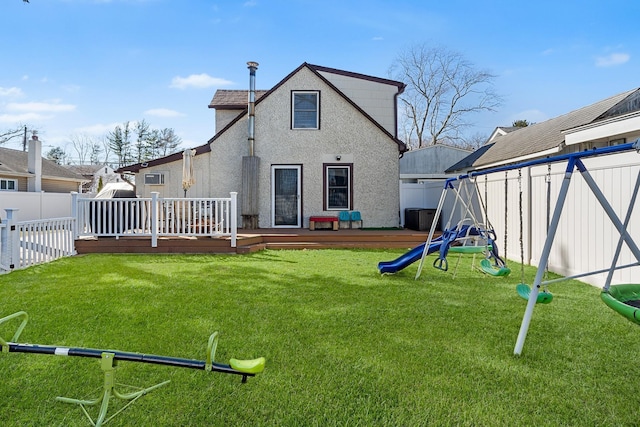 back of house with a yard, a deck, a playground, and a fenced backyard