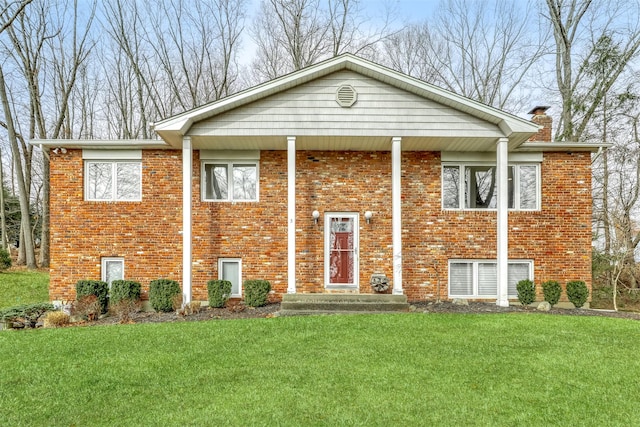 raised ranch featuring a front lawn, brick siding, and a chimney