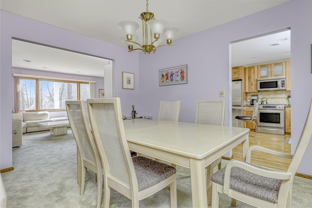 dining area featuring light carpet and a chandelier