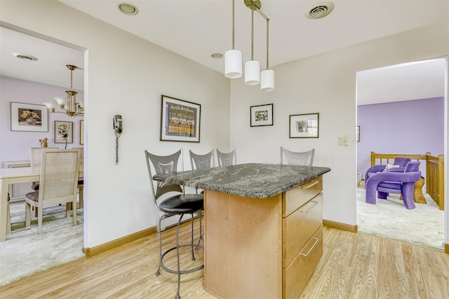 kitchen with a center island, visible vents, a breakfast bar, and light wood-style floors