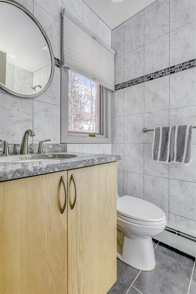 bathroom with vanity, a baseboard radiator, tile walls, toilet, and tile patterned floors