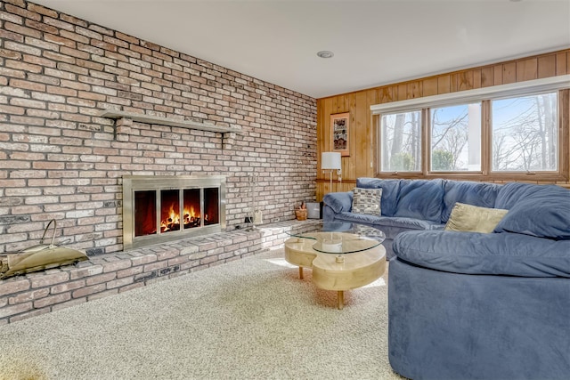 unfurnished living room with a brick fireplace, carpet flooring, and wood walls